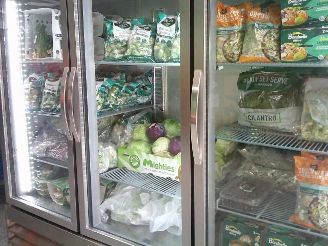 Produce which is mostly salads in a fridge.
